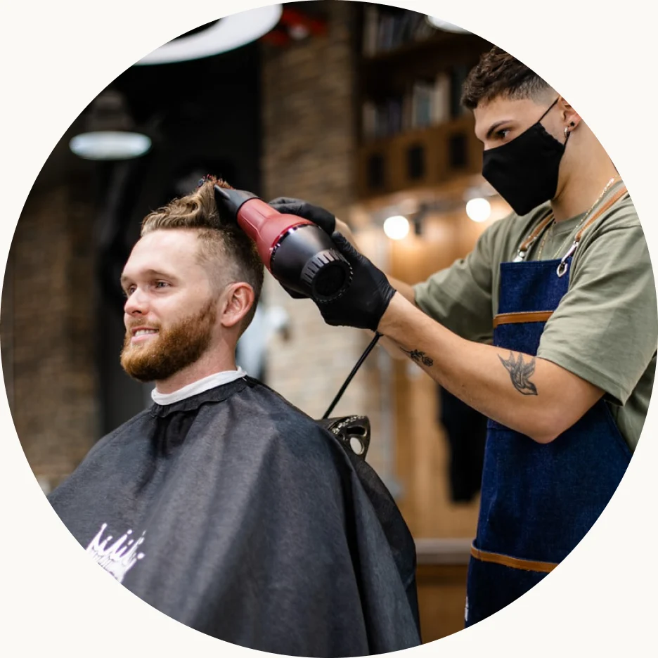 Barber blow-drying a client's hair in a salon